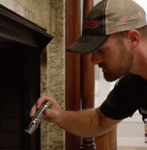 technician using a flash light to look in to a fireplace.