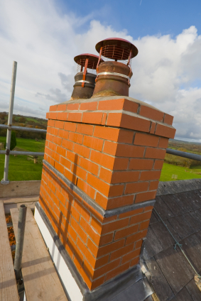 New red brick masonry chimney with two caps-blue sky with clouds in background